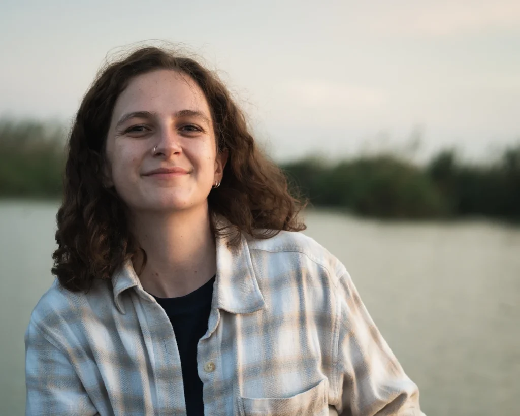 A sunset view of a girl with brown hair smiling.