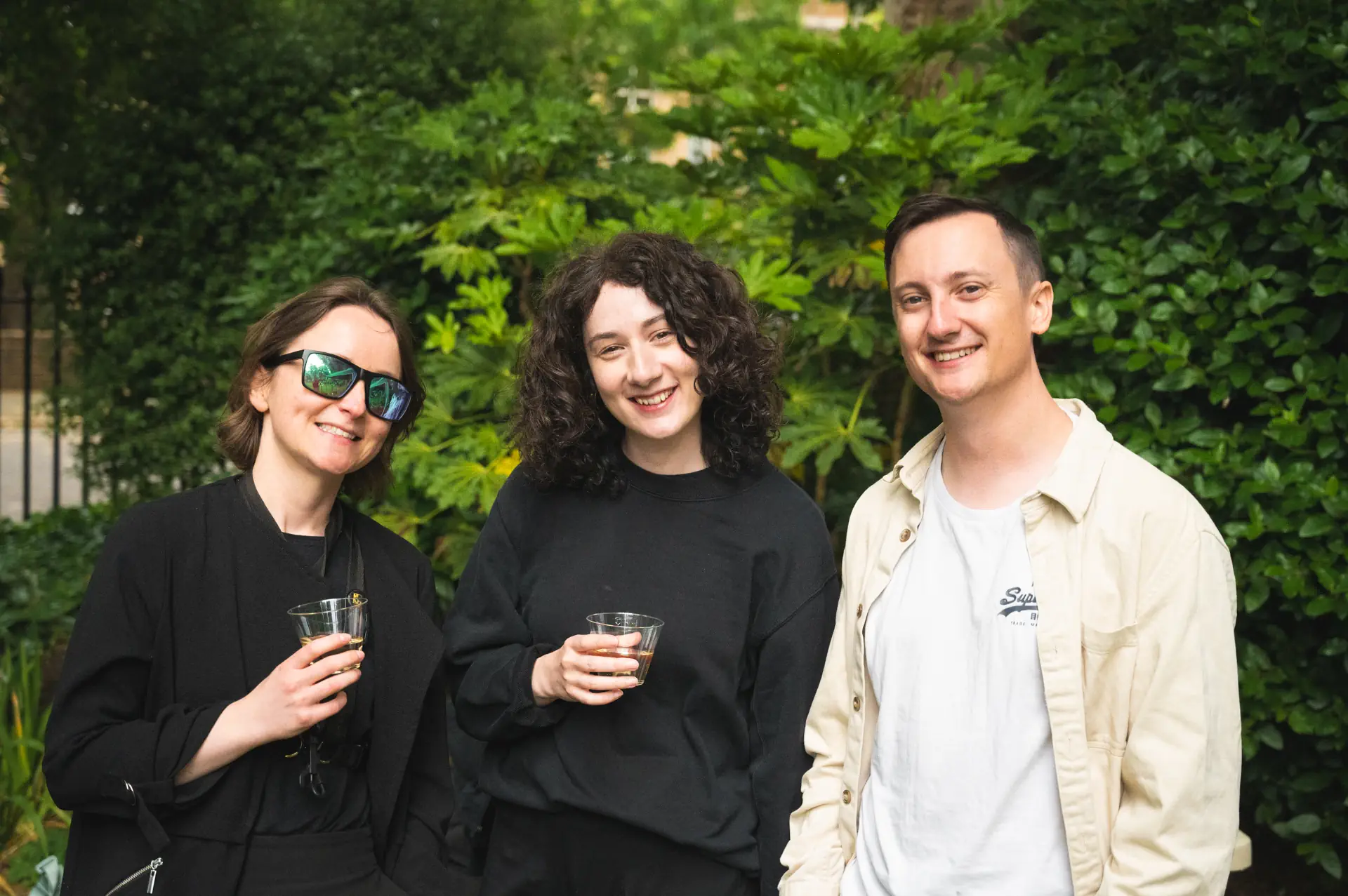Three people demonstrating how to smile in photos naturally during an outdoor photo shoot