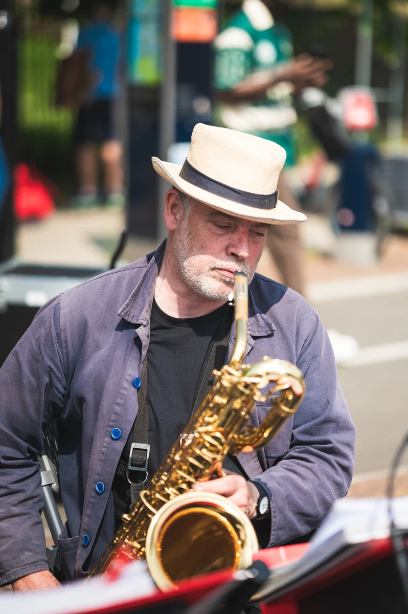 A jazz musician holding a baritone saxophone in a band, waiting for their turn to play