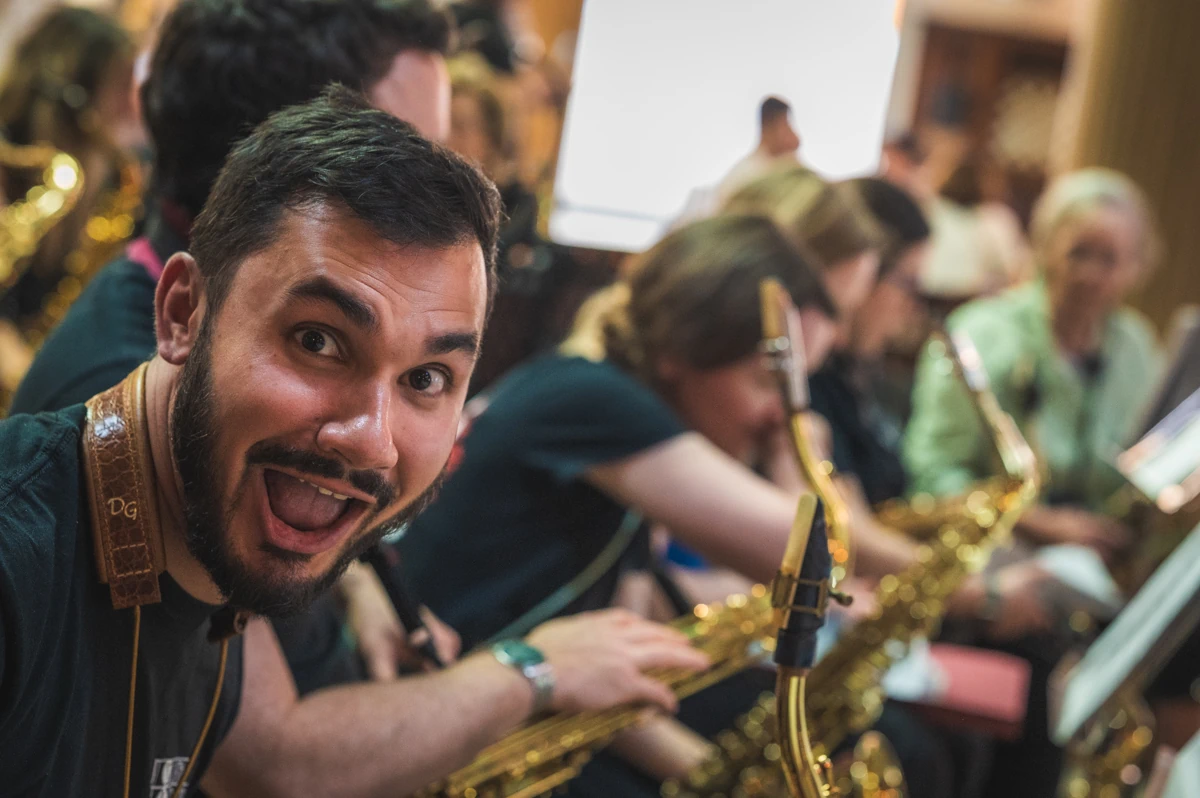 A jazz tenor sax player making a silly face at the camera during a performance