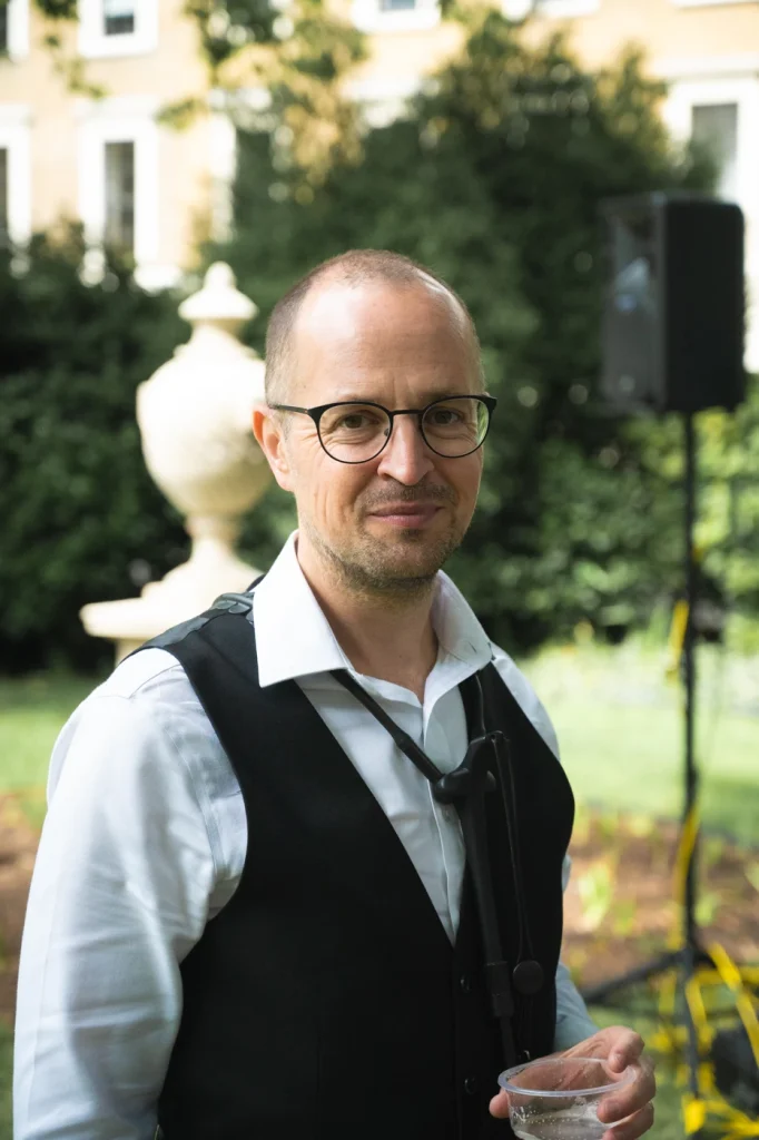 Man in a waistcoat in a garden smiling