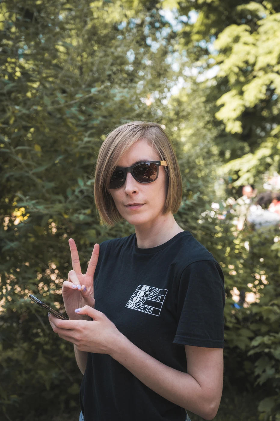 Woman in sunglasses holding a peace sign to the camera