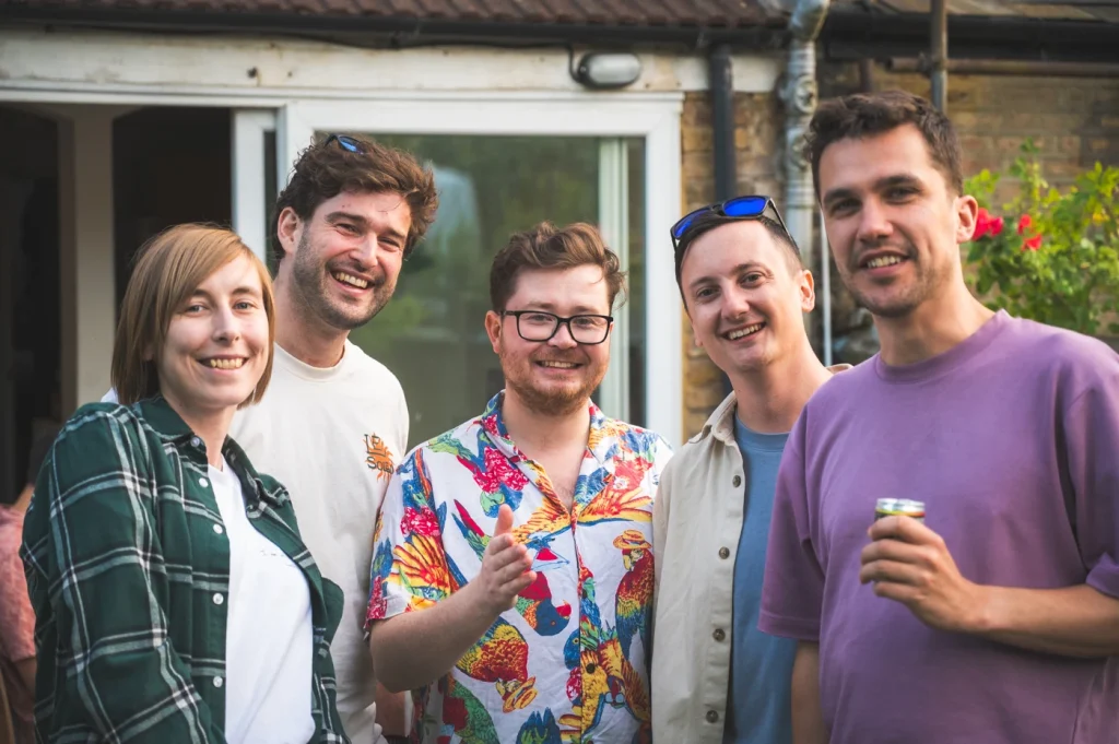 A group of 5 people at a social event, smiling and looking happy.
